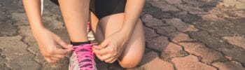 Person tying running shoes, symbolizing building healthy daily habits.