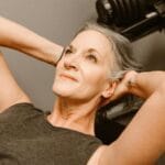 Smiling older woman relaxing with arms behind head, representing healthy aging and wellness at any age