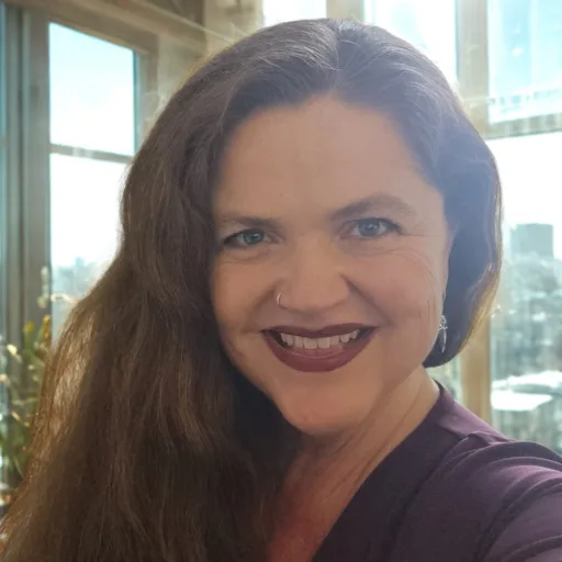 Kandace Blevin smiling indoors with natural light and city view in the background, representing confidence and vibrant living.