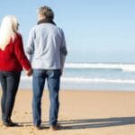 A midlife couple walking hand-in-hand along the beach, symbolizing connection and emotional closeness.